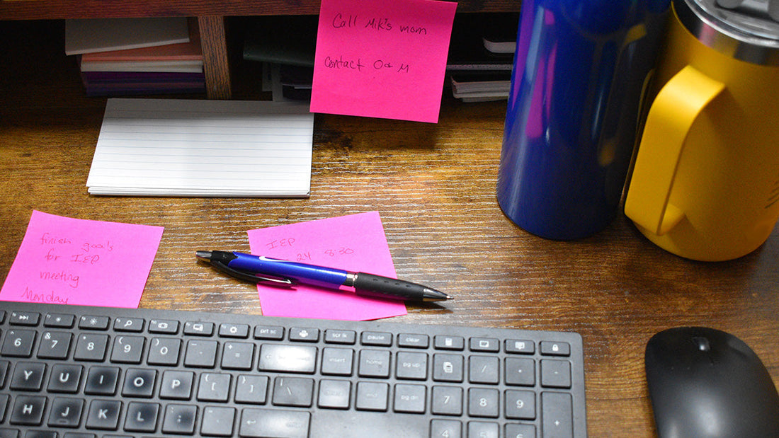  Desk with keyboard and mouse, sticky notes including handwritten notes about finishing goals IEP meeting Monday, Call Mik’s Mom, contact O & M, and IEP at 8:30, insulated travel tumbler and water bottle.